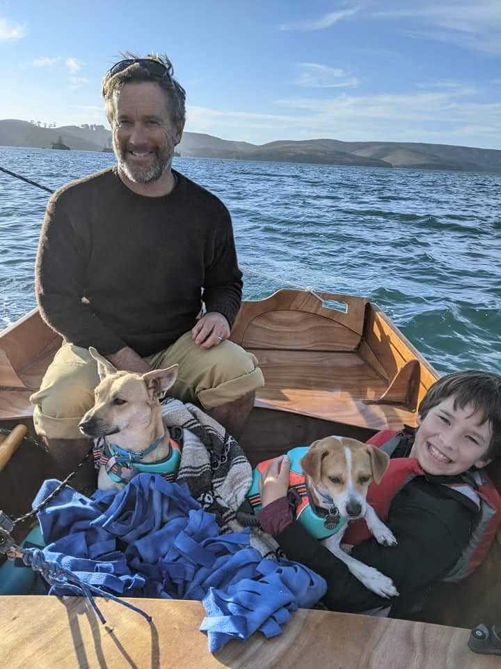 Curtis-Havel-and-son-Declan-sailing-their-home-built-Passagemaker-Dinghy-22Rising-Phoenix22-across-Tomales-Bay-with-our-salty-dogs-Calixo-and-Rocky