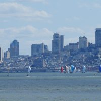 A series of spinnakers parade back from the city toward Corinthian Yacht Club.