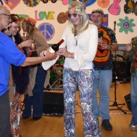 Groovy hippie chick Nora DeGaa accepts the prizes, a bottle of wine and a bar of chocolate, from RYC vice commodore Ernie Galvan.