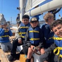 4.	A group of campers smiles at the camera, as they are entertained while sailing in the Bay on Seaward.
