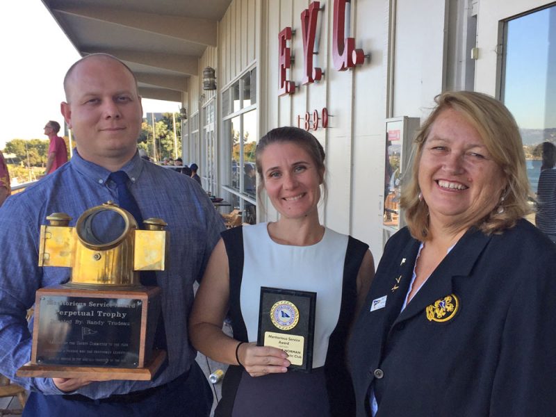 three people with trophy and plaque