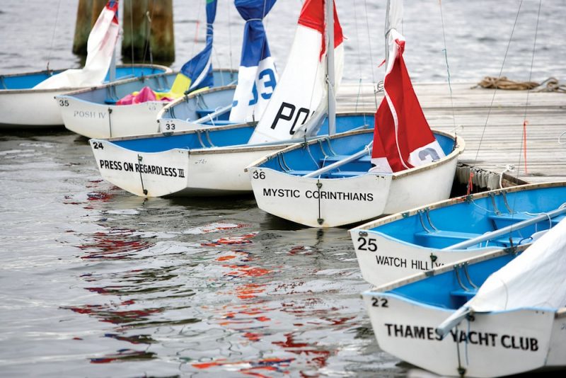 Blue and white Dyer Dhow dinghies lined up at a pier