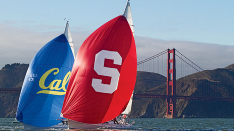 Two J105 sailboats with spinnakers showing Stanford and Cal logos