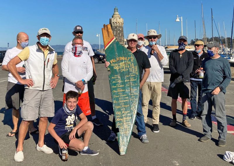 Sailors in parking lot with Folkboat rudder