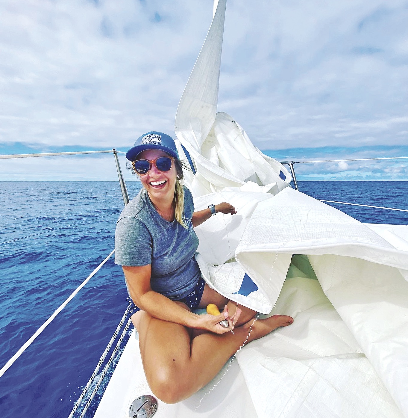 Monique sitting on bow repairing sail