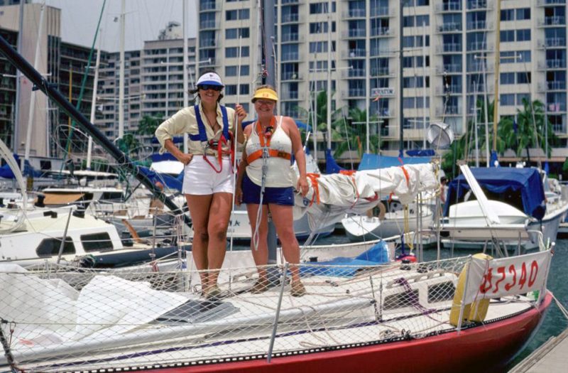 Two women on a red Olson 30, skyscrapers in the background