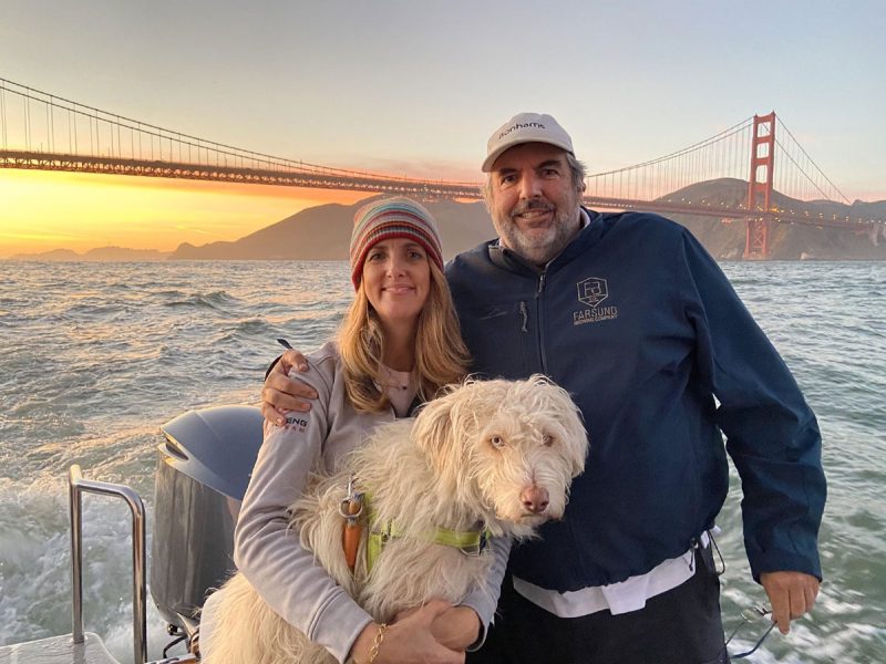 Tina, Cooper and Chris on a boat with the sun setting behind the Golden Gate Bridge