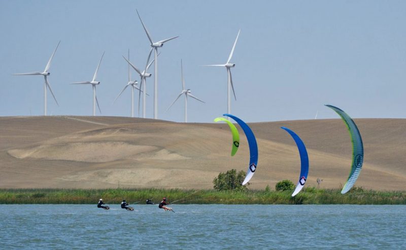 Foiling kites with windmills in the background