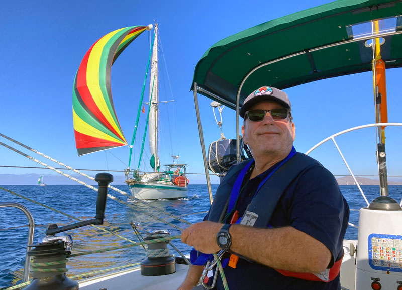 Spinnaker trimming with colorful kite in the background