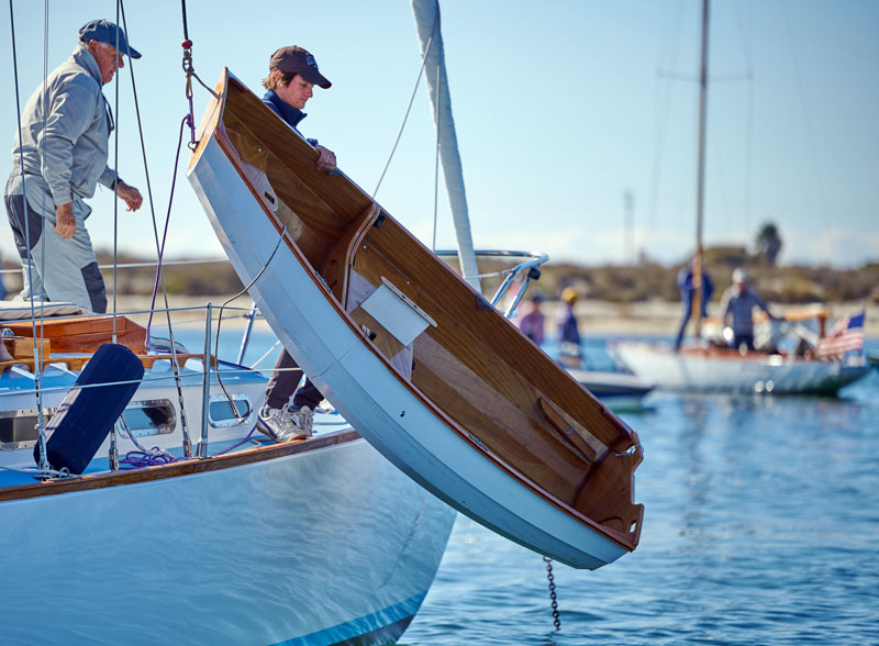 Wood dinghy being hoisted aboard