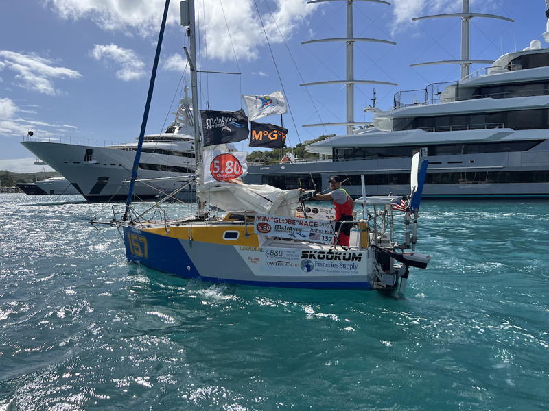 Josh Kali sails by the towering glass and steel megayachts in Falmouth Harbor, Antigua.