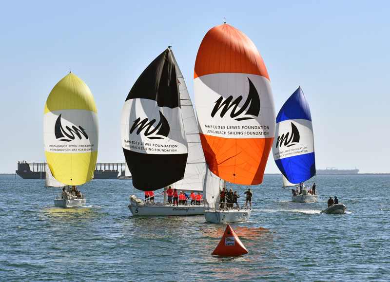 Catalina 37 fleet flying spinnakers approach a mark.