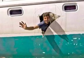 Huub with an optimistic wave from the damaged hull of a new-to-him 38-ft cat.