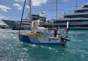 Josh Kali sails by the towering glass and steel megayachts in Falmouth Harbor, Antigua.